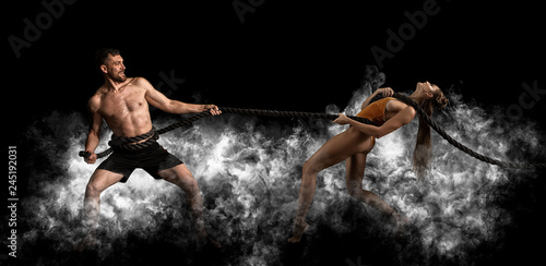 Couple working out with battle ropes at gym