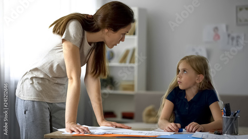 Strict mother criticizing little daughter for drawings, stressed childhood