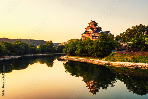 Castle in Okayama, Japan in the morning with river and colorful yellow sky at sunrise