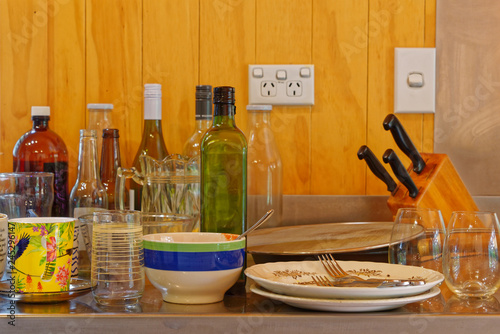 Cluttered dishes and bottles on a stainless steel kitchen sink