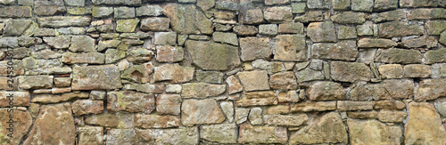 Panorama einer groben, sehr alten Natursteinmauer aus unterschiedlich großen Steinen