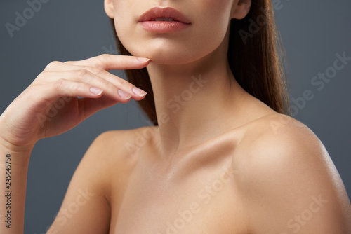 Charming young woman with beautiful full lips posing on blue-gray background