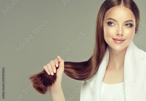 Piękna modelka z błyszczącymi brązowymi i prostymi długimi włosami. Prostowanie keratyny. Zabiegi lecznicze, pielęgnacyjne i spa. Gładka fryzura