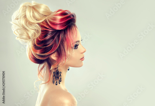 Beautiful model girl with elegant multi colored hairstyle . Stylish Woman with fashion hair color highlighting. Creative red and pink roots , trendy coloring. 