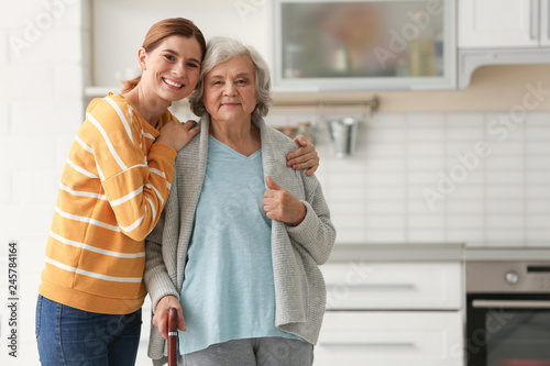 Elderly woman with female caregiver in kitchen. Space for text