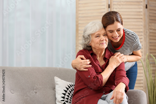 Elderly woman with female caregiver in living room. Space for text