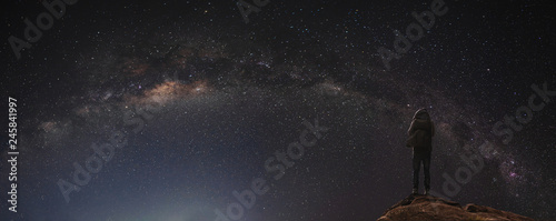 a man standing on the rock enjoying starry sky and milky way at night