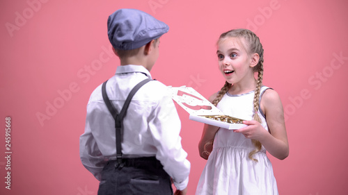 Little boy presenting chocolate candies to surprised girlfriend, Valentines day