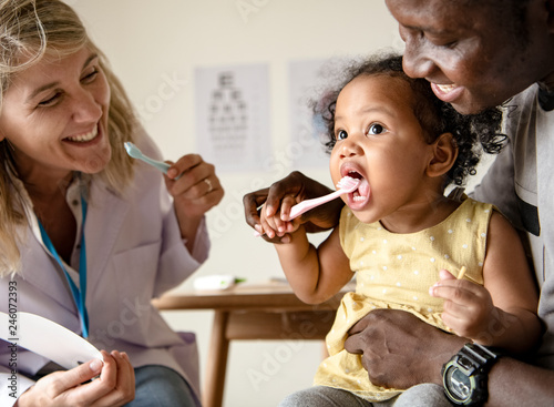 Dentysta uczy małą dziewczynkę, jak myć zęby