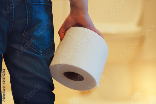 Rare view of kid holding toilet roll in the front of toilet, little boy suffers from diarrhoea holding toilet paper, Low view Child bringing roll of tissue walking to rest room, Children health care