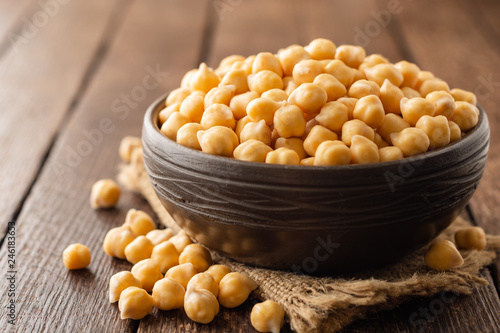 Chickpeas in ceramic bowl on dark wooden rustic table. Selective focus.