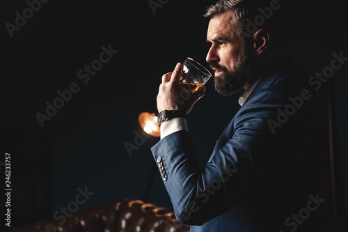 Degustation, tasting. Man with beard holds glass of brandy. Tasting and degustation concept. Bearded businessman in elegant suit with glass of whiskey