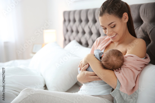 Young woman breastfeeding her baby in bedroom