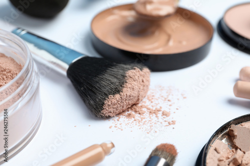 Composition with powder, skin foundation and beauty accessories on white background