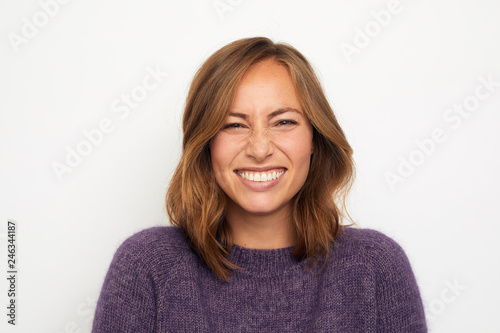portrait of a young happy woman smiling giggles on white background looking in camera