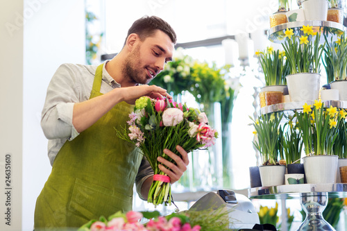 people, business, sale and floristry concept - happy smiling florist man making bunch at flower shop