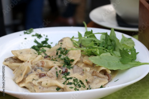 Traditional Slovenian meal called 'Idrijski zlikrofi' - dumplings made from dough with potato filling, served with bacon and mushroom sauce. Selective focus. 