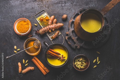 Healthy ingredients of turmeric milk drink with fresh turmeric roots , spices and honey. Hot winter beverage. Immune boosting remedy , detox and dieting concept