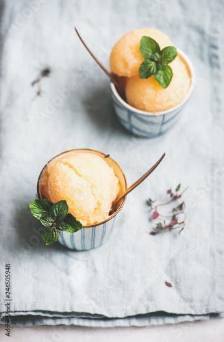 Fresh homemade grapefruit sorbet ice cream scoops in ceramic cups over linen napkin. Healthy vegan summer dessert
