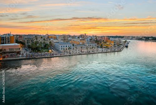 View from a cruise ship as the Piazza Vittorio Emanuele II fills with tourists enjoying a late summer evening sunset at the port city of Brindisi Italy on the Adriatic Coast in the Puglia region.