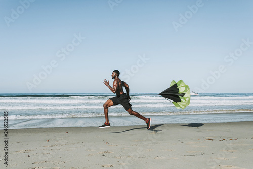Fit man with a running parachute at the beach
