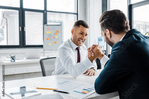 handsome businessman competing arm wrestling with coworker in modern office