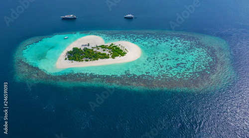 Aerial of beautiful heart shaped tropical island in blue sea at Maldives paradise panoramic background