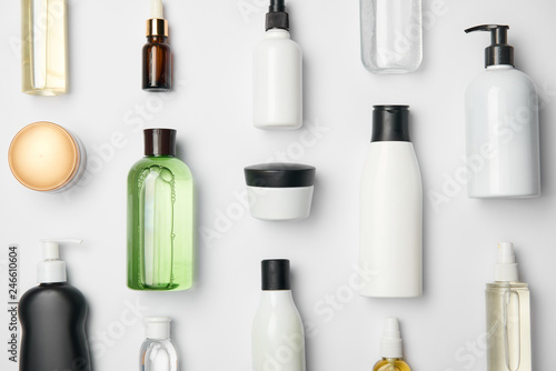 Top view of different cosmetic bottles and container on white background