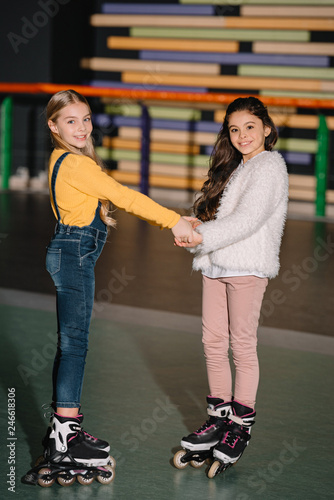 Selective focus of beautiful children on roller skates smiling and holding hands