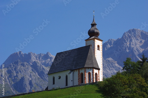 Kościółek na wzgórzu a Alpami w tle
