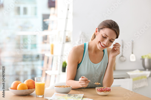 Young woman in fitness clothes having healthy breakfast at home