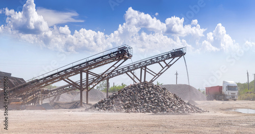 Crushing machinery, cone type rock crusher, conveying crushed granite gravel stone in a quarry open pit mining. Processing plant for crushed stone and gravel. Mining and Quarry mining equipment.