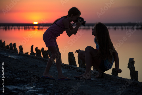 on a salt lake two girls take pictures of each other at sunset