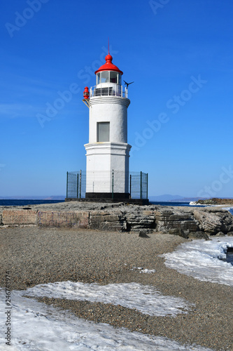 Russia. Vladivostok. The lighthouse of Egersheld(1876 year built) Tokarevskaya koshka in winter sunny day in Amur bay