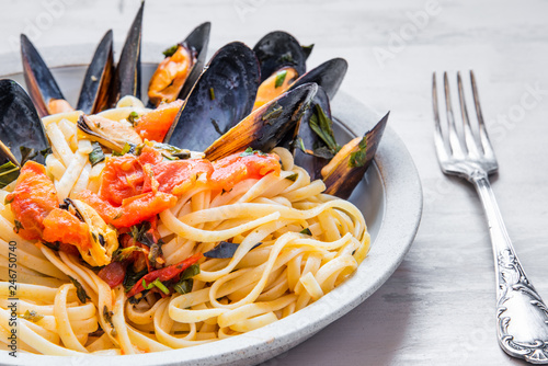 Traditional Italian pasta linguine with mussels on a plate close-up.