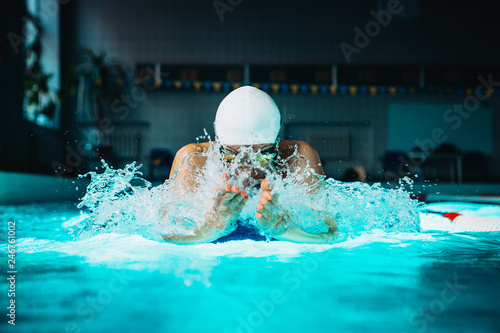 Professional woman swimmer swim using breaststroke technique on the dark background