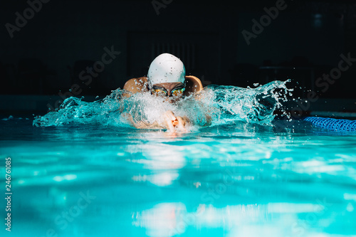 Professional woman swimmer swim using breaststroke technique on the dark background