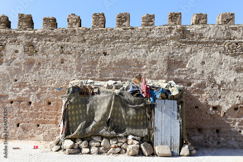 Homeless Bum street people architecture in Essaouira, Morocco. House made of rocks and sheets in front of city defensive wall.