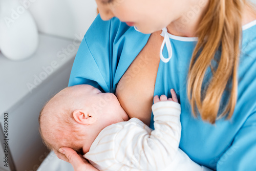 cropped shot of young mother breastfeeding newborn baby in hospital room