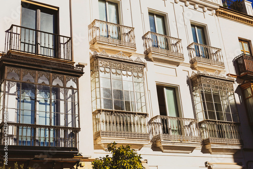 Traditional facades of houses with twisted wrought and carved balconies of the city of Seville, Andalusia, Spain.