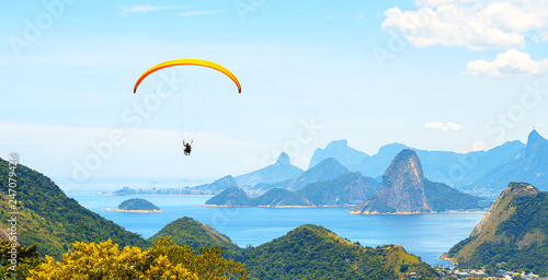 A colorful parachute with skydiver on sunny blue sky background. Active lifestyle. Extreme sport. Concept of holidays, vacation, tourism. horizontal. Aerial view of Rio de Janeiro with turquoise water