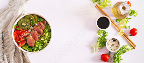 Poke bowl. Buddha bowl. Traditional salad with pieces of medium-rare grilled Ahi tuna and sesame with fresh vegetable salad and rice on a plate. Top view. Copy space. Banner
