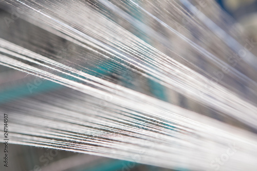 Close up macro detail of Yarn thread lines running in the weaving loom machine. Yarn bobbins making in a textile factory.