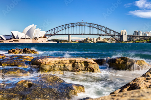 sydney harbour view with opera house, bridge and rocks in the foreground