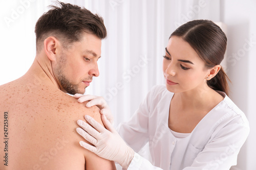 Doctor examining patient in clinic. Visiting dermatologist