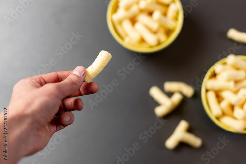 Hand holding corn puffs over table