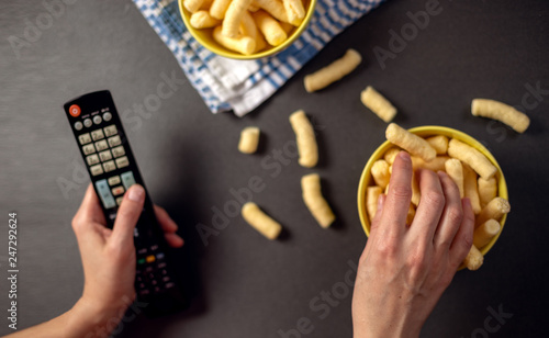 Person watching a TV and eat snacks, corn puffs