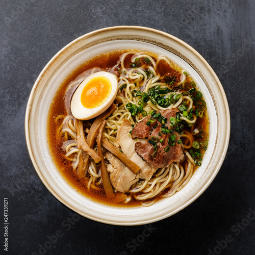 Ramen asian noodle in broth with meat and Ajitama pickled egg in bowl on dark background