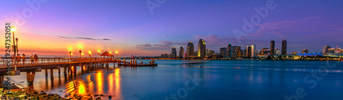 Panorama of Coronado old pier reflecting on in San Diego Bay from Coronado Island, California, USA. San Diego cityscape skyline with Downtown and Waterfront Marina District at twilight on background.