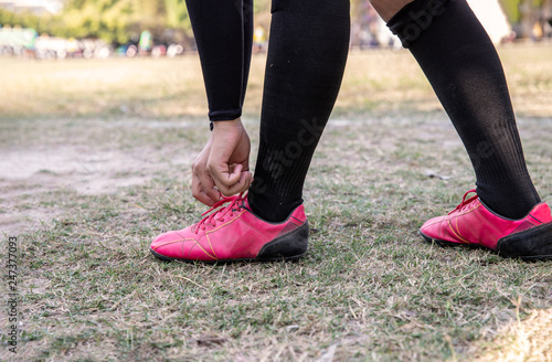 Young woman exercising in soccer field, Young woman workout outdoor for her healthy and office girl lifestyle. She was tying her shoes tightly